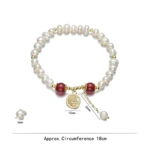 Freshwater pearl bracelet with gold Fu pendant and red agate beads on white background