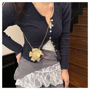 Close-up of golden fish-shaped evening bag with detailed scale texture and chain strap