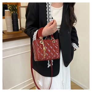Close-up of red patent leather mini handbag featuring classic quilted pattern and gold charms