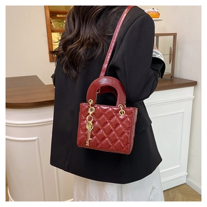 Macro detail of wine red patent leather with classic quilted stitching and metal charm