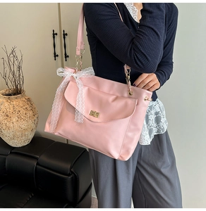 Sac à bandoulière rose avec nœud en dentelle blanche et fermoir rotatif doré