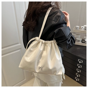 Sac seau blanc avec cordon de serrage et nœud argenté porté à l'épaule par un mannequin
