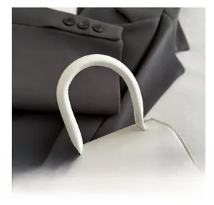 Detail of white mini bag with rounded top handle and metallic silver bow ornament