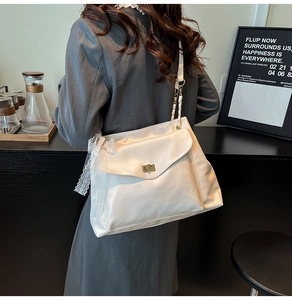 Détail du sac crème avec fermoir rotatif doré et décoration élégante en nœud de dentelle