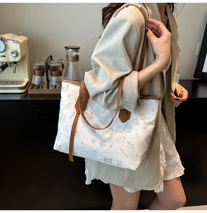 Detail of trendy cream tote bag with brown leather handles and playful floral prints