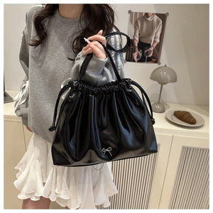 Détail d'un sac à cordon noir brillant avec une boucle en métal en forme de nœud argenté
