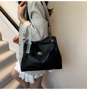 Détail du sac cabas en cuir noir avec fermoir doré et bordure en dentelle blanche élégante