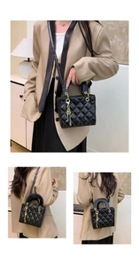 Detailed view of the black quilted leather texture and gold key charm on the handbag