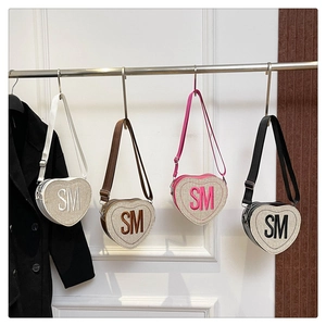 Détail de sacs bandoulière en forme de cœur avec texture tressée et patchs lettres SM