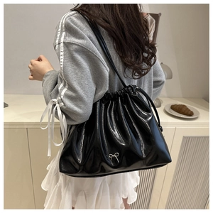 Détail du sac à bandoulière noir brillant avec cordon plissé et nœud en métal argenté