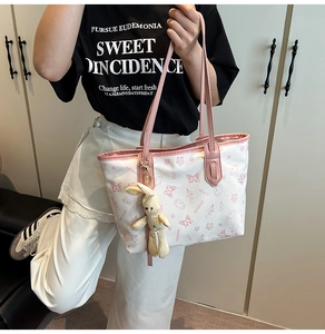 Detail of white tote bag with pink cartoon prints, faux leather straps and plush bunny