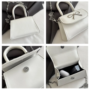 Detail view of mini white PU leather bag with silver bow buckle and chain strap