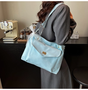 Close-up of light blue tote bag featuring a gold turn-lock and white lace bow detail