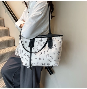 Close-up of white tote bag featuring black cartoon puppy prints and dual handle design