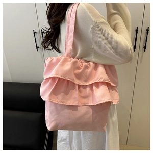 Detail van roze tote bag met ruches en grote golvende randen gedragen over de schouder