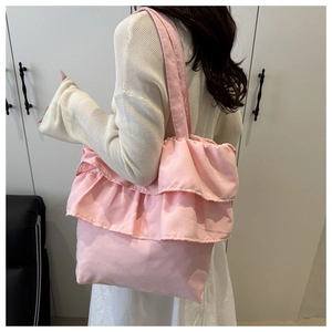 Detailed view of pink ruffled tote bag worn over the shoulder by a model