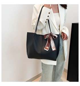 Detail of black PU leather tote bag featuring a decorative printed silk scarf and split seam