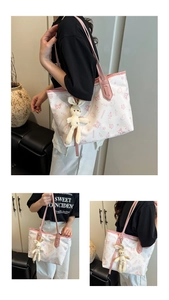 Detail view of a white tote bag with pink butterfly prints and a cute rabbit plush charm
