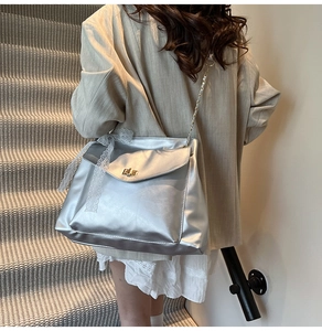 Details der silbernen Metallic-Tasche mit Spitzenschleife und Kettenriemen