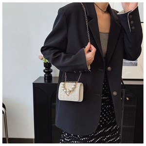 Detail of straw woven crossbody bag with pearl handle and heart-shaped twist lock buckle