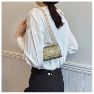 On-body view of a mini gold rhinestone crossbody bag with metal chain and twist lock