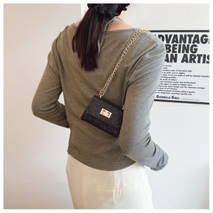Sac bandoulière chic en tweed noir avec chaîne dorée porté par un mannequin mode