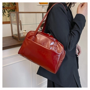 Close-up of red patent leather tote bag showing side pocket and glossy texture on model