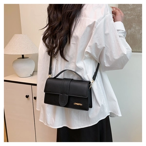 Detail of black crossbody bag with golden JINGPIN logo and smooth leather texture