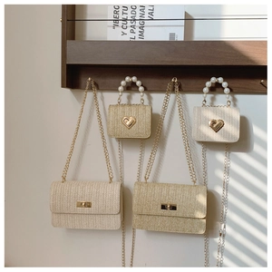 Detail of straw woven bags featuring pearl handles, heart clasps, and chain straps