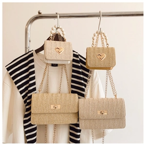 Straw woven bags featuring pearl handle and metal chain in a boutique display