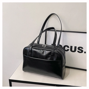 Macro detail of glossy black PU leather tote bag featuring a durable silver metal zipper