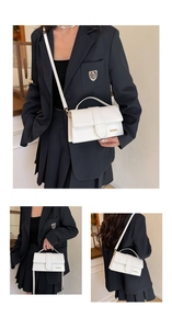 Detail of white leather handbag showing top handle and adjustable shoulder strap