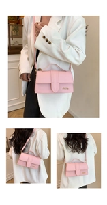 Detail view of pink leather crossbody bag with top handle and gold logo metal buckle
