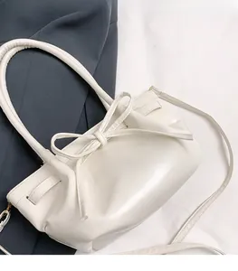Detail of white bucket bag featuring a large bow knot and drawstring closure design