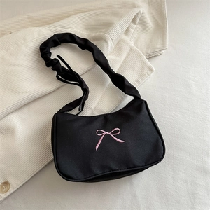 Dettaglio della borsa a spalla nera con ricamo a fiocco rosa e tracolla arricciata