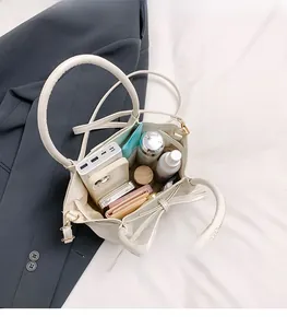 Top view of spacious interior storage for white bucket bag with items and makeup