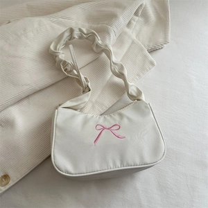 Dettaglio borsa baguette crema con ricamo a fiocco rosa e tracolla con effetto arricciato
