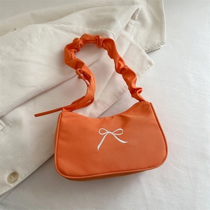 Dettaglio borsa hobo arancione con ricamo a fiocco bianco e tracolla a pieghe chic