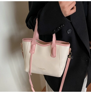 Detail of elegant cream tote bag with pink straps and fashion leather text on black suit
