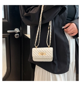 Chic cream mini crossbody bag with diamond quilting and gold chain strap on model