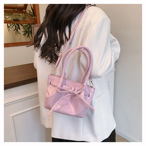 Detailed view of pink PU leather bucket bag with bow decoration and adjustable strap