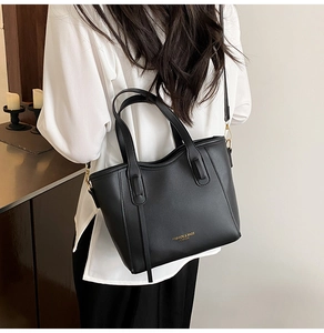 Detail of a chic black leather bucket bag with gold lettering and adjustable crossbody strap