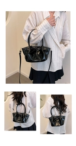 Detail of black glossy bucket bag with bow tie and adjustable golden hardware strap