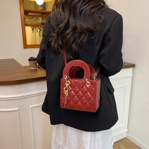 Elegant red quilted leather handbag with gold charms shown in a stylish interior setting