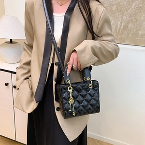Quilted black crossbody bag with gold key charms and metal top handles shown on model
