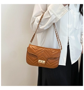 Detail of a brown chevron quilted shoulder bag with gold twist lock and chain strap