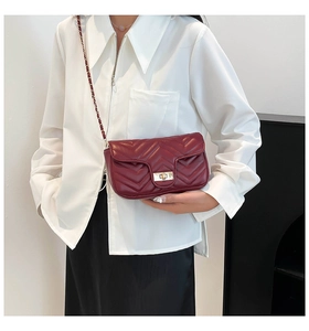 Detail of burgundy quilted crossbody bag with V-pattern and golden twist lock