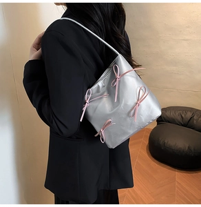 Detail of silver metallic balletcore shoulder bag with delicate pink ribbon bows