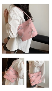 Detail view of pink bucket bag with silver bow accents and slender shoulder strap