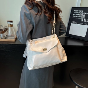 Sac à bandoulière beige chic avec nœud en dentelle porté par un mannequin au café